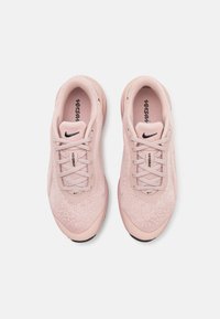 Ljusrosa träningsskor med textilöverdel med struktur, rund tå och vadderad sula. Har logotyp och snörning för en säker passform.