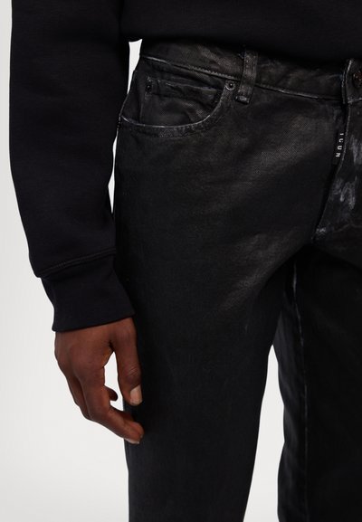 Black denim jeans with a textured finish, five-pocket design, and subtle distressing details. Paired with a dark sweatshirt.