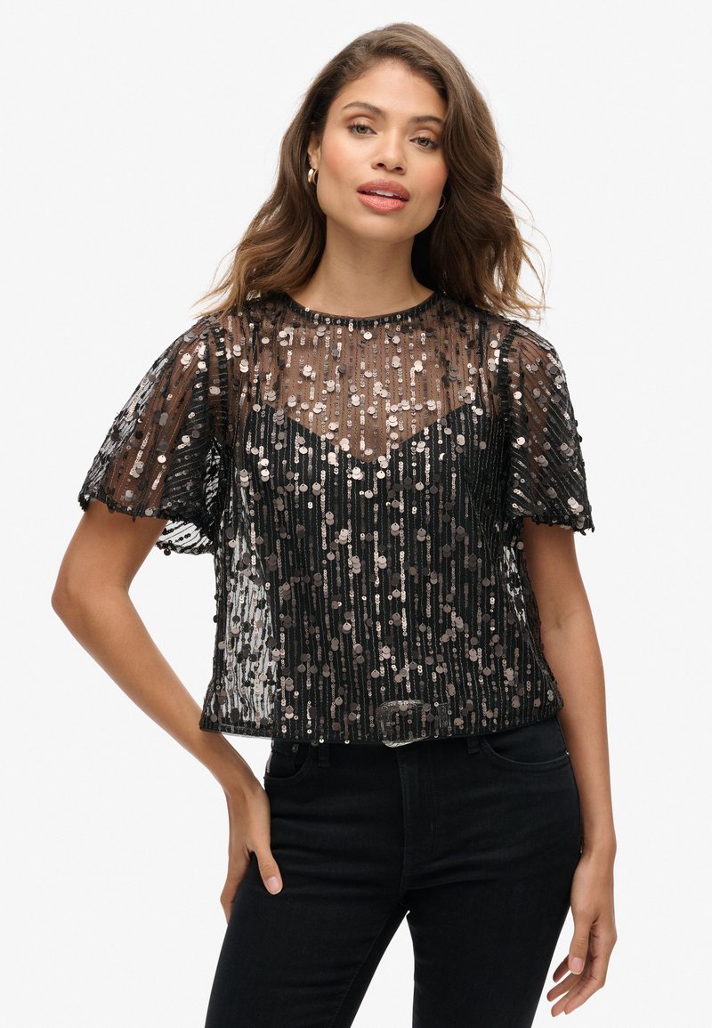 Zwarte cropped top van doorschijnende stof versierd met metalen pailletten. Heeft korte mouwen en een ronde halslijn. Textuur- en gelaagde ontwerpen.