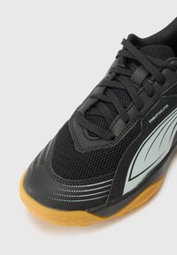 Schwarzer Sportschuh mit strukturiertem Mesh-Obermaterial, reflektierenden Akzenten und einer Gummisohle, die für Stabilität und Grip sorgt.