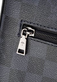 Pelle testurizzata blu navy con cerniera argento dotata di cursore con marchio. La chiusura a cerniera è cucita con precisione e funzionale.