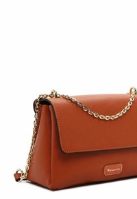Brown textured synthetic handbag with a gold chain strap and a flap closure. Features a logo plate on the front. Triangular shape.