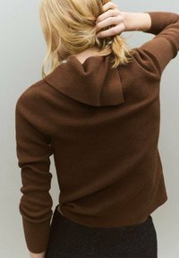 Pull en maille côtelée marron avec une capuche, doté de manches longues et d'une finition texturée. Le vêtement est porté de dos, montrant des détails minimaux.