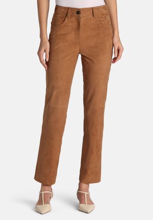 Pantalon en daim marron à la coupe cintrée, avec une fermeture à boutons à l'avant, des passants pour ceinture et des poches latérales, associé à des talons couleur crème.
