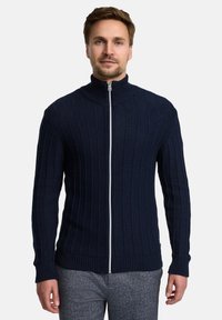 Marineblauer, gerippter Reißverschluss-Pullover mit hohem Kragen, ausgestattet mit einem weißen Reißverschluss und enganliegenden Bündchen. Hergestellt aus strukturiertem Stoff für Wärme.