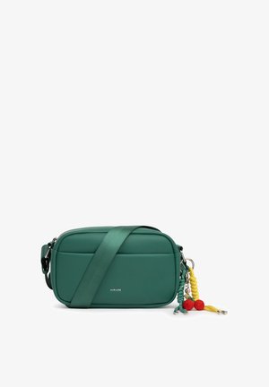 Sac bandoulière rectangulaire vert avec une large sangle et des porte-clés à pompons tressés colorés, étiqueté "MIRIADE" au centre avant.