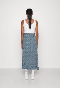 Květinová maxi sukně s námořnickým základem, která má malý vzor zelených a modrých květin, elastický pas a volánkový spodní lem.