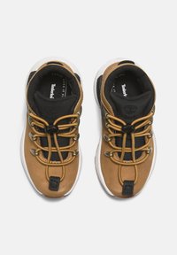 Zapatillas de cuero marrón y malla negra con cordones elásticos, que cuentan con una suela blanca y un logo prominente en la plantilla.