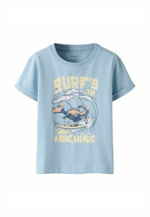 Light blue cotton t-shirt with short sleeves, featuring a graphic design of a surfing cat and the text "SURF'S UP SURF MACHINE" in yellow.