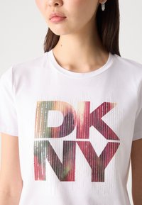 Weiße Baumwoll-T-Shirt mit großem, mehrfarbigem "DKNY"-Logo mit einem glitzernden Farbverlaufseffekt, Rundhals, kurzen Ärmeln und glatter Textur.