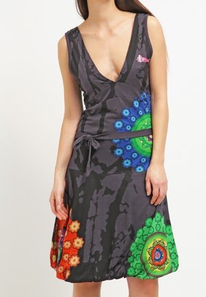 Ärmelloses schwarzes Kleid mit tiefem V-Ausschnitt, tailliert und mit bunten kreisförmigen Blumenmustern in Blau, Rot und Grün auf Rock und Oberteil.