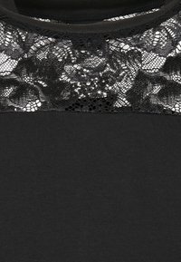 Black t-shirt featuring a lace upper bodice, with floral patterns. The lower section is smooth and untextured, providing contrast.