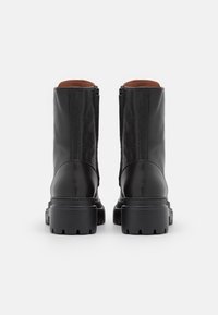 Černé kožené kotníkové boty s texturovaným povrchem, se zipovým uzávěrem, hnědým podšívkovým materiálem a silnými gumovými podrážkami.