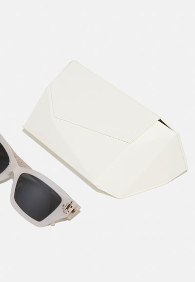 Sunglasses with a translucent light gray frame and dark lenses, accompanied by a white, geometric hard case with a smooth texture.