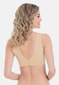 Beige drahtloser BH mit tiefem V-Rücken, breiten Trägern und nahtlosem Design. Hergestellt aus glattem Stoff und ausgestattet mit einem diskreten Hakenverschluss.