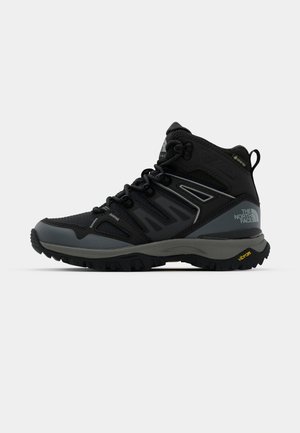 Bottes de randonnée mi-hauteur en noir et gris. Présentent une tige texturée, une pointe renforcée et une semelle Vibram pour une meilleure adhérence. Conception légère.