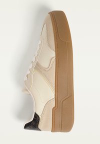 Beżowe sneakersy z teksturowaną skórzaną cholewką, gumową podeszwą i zaokrąglonym noskiem. Posiadają białe sznurowadła oraz ciemny wzorzysty akcent przy pięcie.