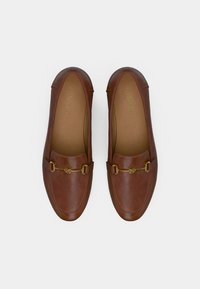 Chaussures à enfiler en cuir marron avec des accents métalliques dorés et un bout arrondi. Texture lisse et détails de couture subtils.