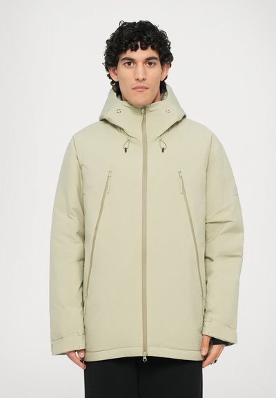 Veste rembourrée vert olive clair avec un col haut, deux zips à l'avant, des poches latérales et des cordons ajustables sur la capuche.