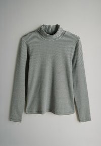 Zwart-wit horizontaal gestreepte langmouw turtleneck shirt liggend op een lichtgrijze achtergrond.