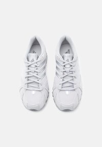 Valkoiset urheilukengät, joissa on verkkopäällinen, hopeanhohtoiset yksityiskohdat, pehmustettu pohja ja perinteinen nauhoitus turvalliseen istuvuuteen.