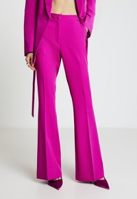 Eng anliegende, hoch taillierte Hose aus leuchtend pinkem Stoff, an den Knöcheln ausgestellt, mit Seitentaschen, einem einzelnen Knopfverschluss und glatter Textur.