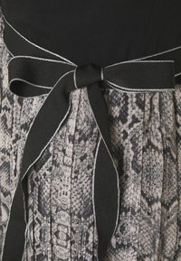 Plisseret kjole med en sort top og en slangeskindsprintet nederdel i nuancer af grå, med et sort bånd i taljen fremhævet af sølvsting.