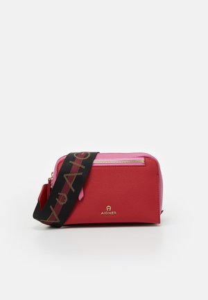 Sac bandoulière en cuir rouge et rose avec fermeture éclair dorée et sangle noire ajustable marqué "Aigner" en lettres dorées.