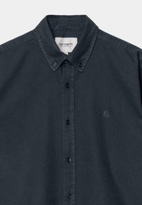 Camisa de algodón azul oscuro con cuello extendido, botones negros y un pequeño logo bordado en el lado izquierdo. Textura suave.