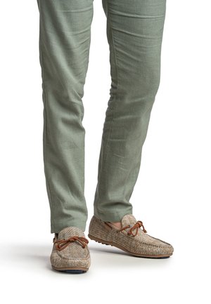 Lichtbruine loafers met een geweven ontwerp, veters en contrasterende tan accenten. Gecombineerd met op maat gemaakte groene linnen broek.