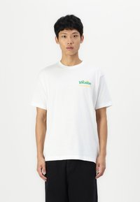 White cotton t-shirt with a round neckline. Features a colorful "On Vacation" graphic on the left chest. Short sleeves, relaxed fit.