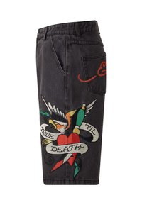 Shorts in denim neri con un design ricamato colorato che presenta un cuore e un'aquila, insieme al testo "TRUE TILL DEATH" su un banner.