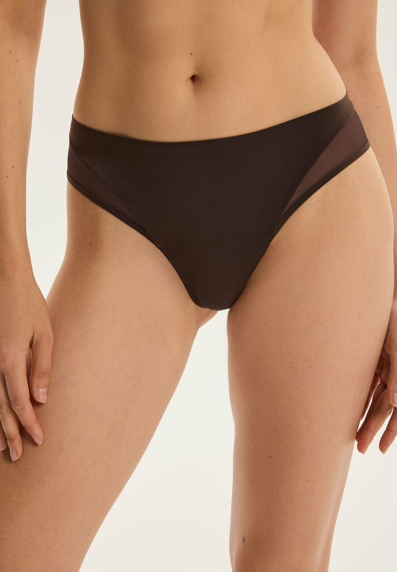 Czarny bikini o wysokim stanie, wykonany z gładkiego materiału z przezroczystymi bocznymi panelami. Charakteryzuje się minimalistycznym wzornictwem i umiarkowanym krojem.