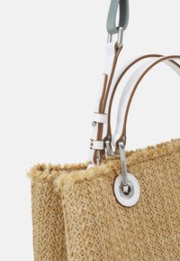 Vävda halmväskor med fransar, utrustade med vita och bruna läderremmar samt en cirkulär detalj i silverfärg.