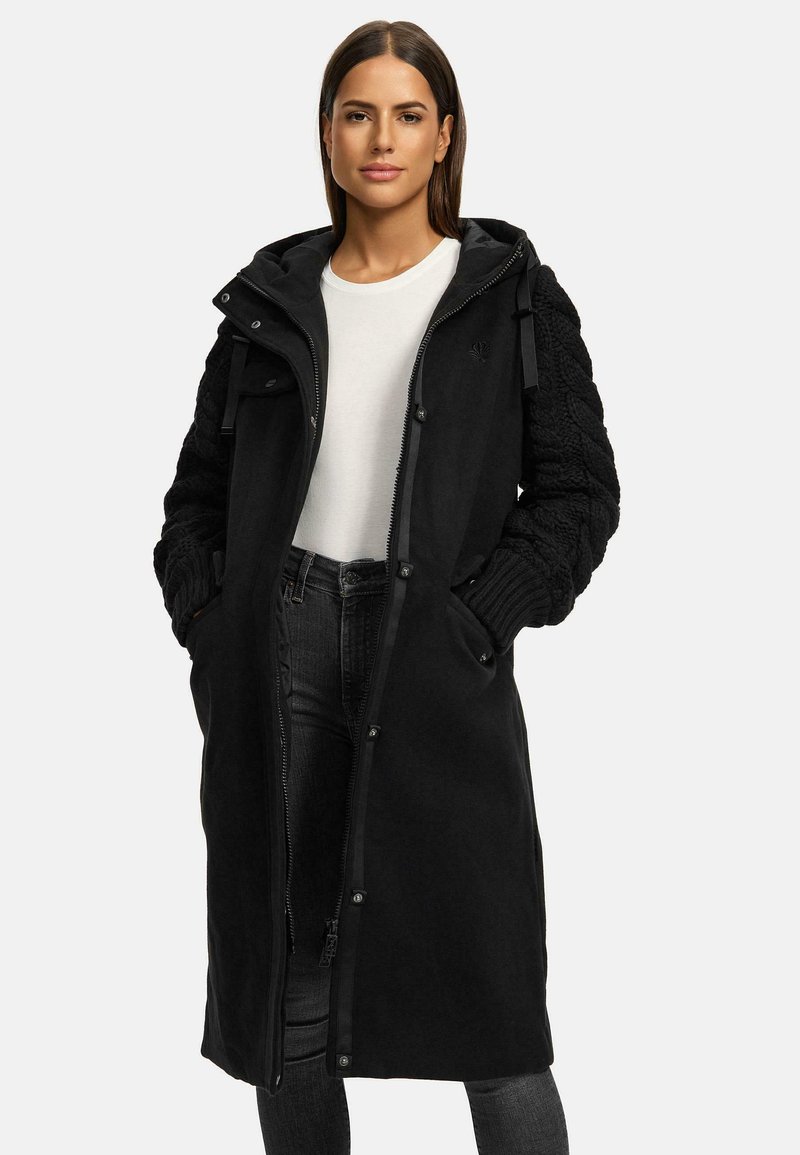 Black long coat with a zip front and snap buttons. Features knitted sleeves and a hood. Made from soft fabric, offering a modern design.