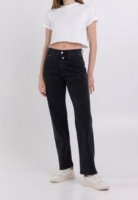 Svarta högmidjade jeans med raka ben, fem fickor och lätt urtvättning. Kombineras med en kortärmad vit t-shirt och vita sneakers.