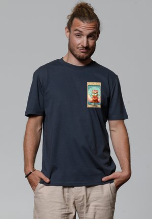 Marineblauwe katoenen T-shirt met een kleurrijke grafische print op de borst, die een karakter en tekst toont, omgeven door een decoratieve rand.