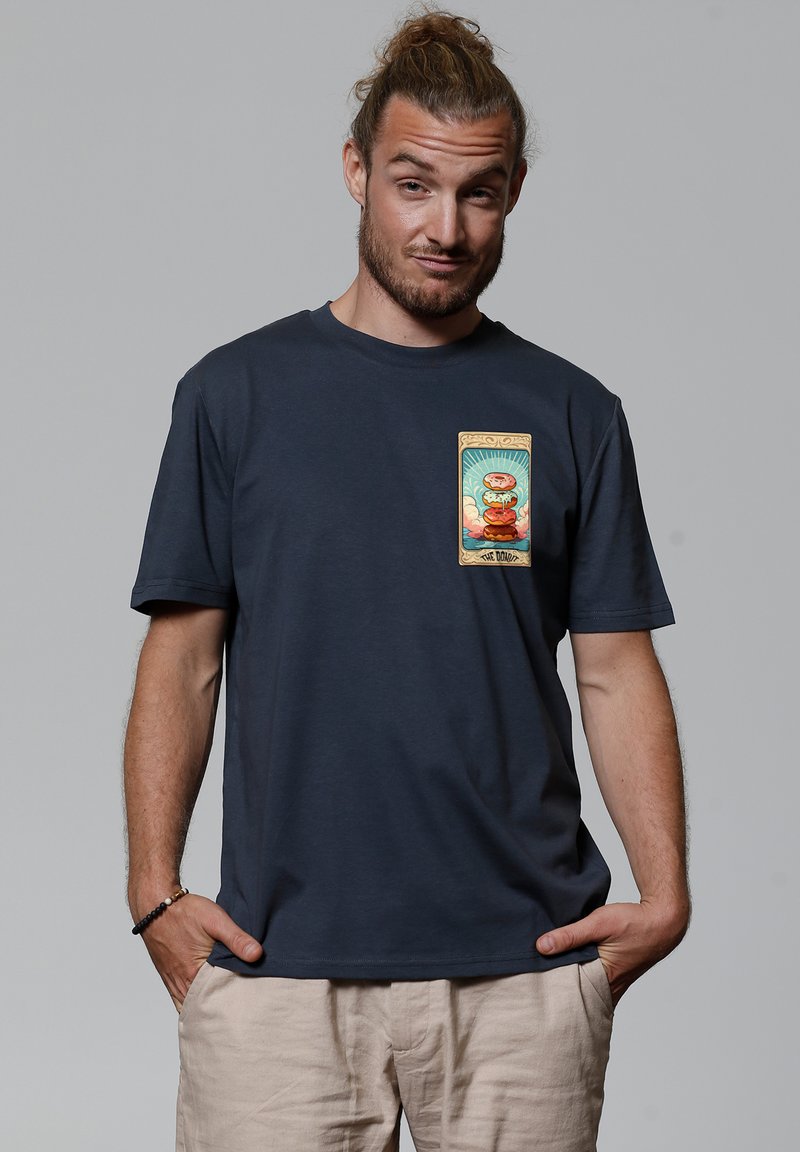 Navyblaue Baumwoll-T-Shirt mit einem bunten Grafikdruck auf der Brust, der eine Figur und einen Text zeigt, die in einem dekorativen Rahmen eingefasst sind.