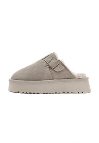 Pantofole slip-on in pelle scamosciata di colore grigio chiaro, con una morbida foderatura in shearling, dettagli con doppia fibbia e suola spessa in gomma con battistrada testurizzato.