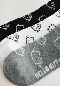 Drie paren enkelsokken in zwart, wit en grijs, voorzien van herhaalde Hello Kitty ontwerpen in een zachte, gebreide textuur.
