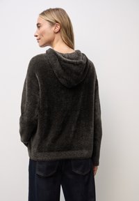 Pullover con cappuccio, grigio scuro e morbido, dal fit rilassato. Caratterizzato da un tessuto testurizzato e da un orlo largo, abbinato a jeans blu scuro.
