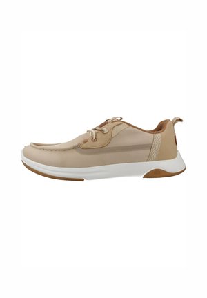 Zapatilla casual beige con suela blanca, diseño con cordones, parte superior de malla y cuero, y lengüeta en el talón para facilitar su uso.