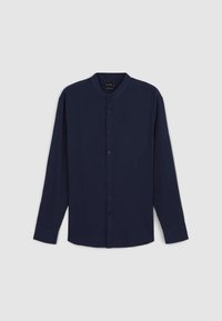 Chemise bleu marine à manches longues avec col montant, boutonnage sur le devant et texture lisse. Présente une coupe décontractée et un ourlet arrondi.