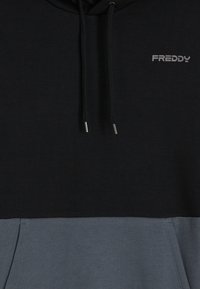 Felpa con cappuccio nera e grigio chiaro con cordoncini. Il materiale è un morbido misto cotone. Presenta un logo "FREDDY" ben visibile in grigio sul petto.