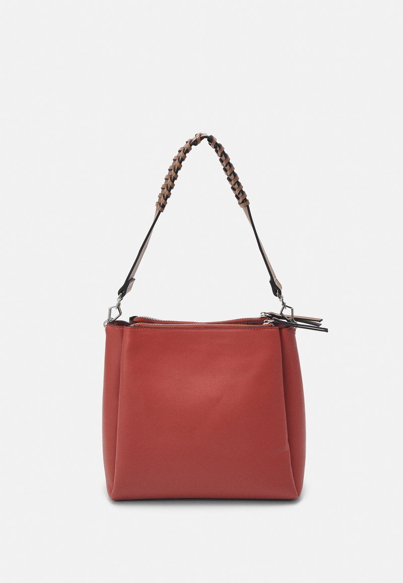 Sac à main en cuir rouge avec poignée tressée marron et noire et fermeture éclair supérieure, présenté sur un fond blanc uni.