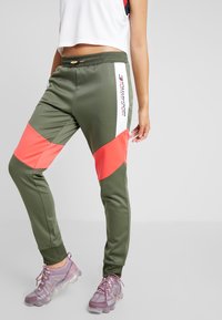 Olivgröna joggers med korallfärgade och vita geometriska paneler; elastisk midja; tryckt logotyp på sidan; slät, lätt tyg.