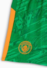 Maglia sportiva verde con design testurizzato, dotata di accenti arancioni e del logo del Manchester City sull'orlo.