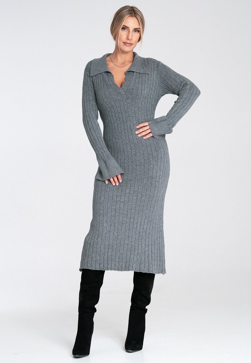 Szara dzianinowa sukienka z golfem, długimi rękawami i dopasowanym krojem, sięgająca do połowy łydki. Noszona z czarnymi botkami sięgającymi do kolan.