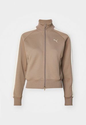 Rudas zip-up sportinė striukė su aukštu apykakle, kreminės spalvos šoninėmis juostomis ir susiraukšlėjusiais rankogaliais bei apačia. Yra logotipas kairėje krūtinės pusėje.