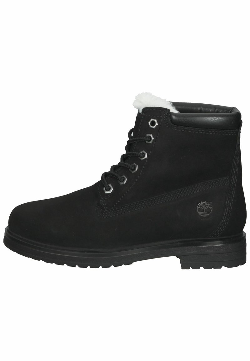 Bottes cheville en suède noir avec un col bordé de polaire blanche matelassée, œillets métalliques et semelle en caoutchouc texturée. Logo embossé sur le côté.